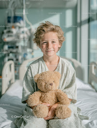 Joyful Young Child Holding Teddy Bear in Bright Hospital Room