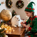 Girl in Elf Costume Playing with Dog by Christmas Decor