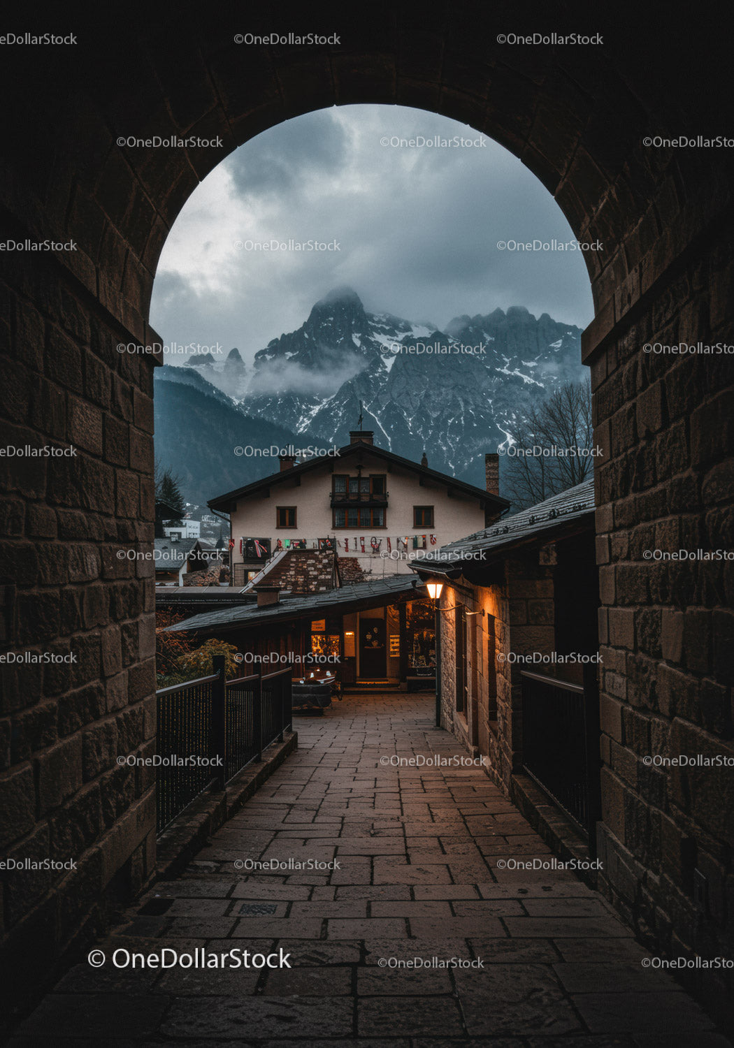 Cozy mountain village view through old stone archway