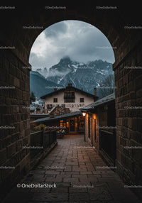 Cozy mountain village view through old stone archway