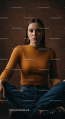 Stylish Woman in Mustard Sweater Sitting Cross-Legged Against Neutral Background