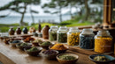 Herbal Spices in Glass Jars and Bowls on Wooden Table with Green Background