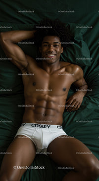 Smiling muscular man relaxing on dark green bed linen