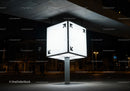 Illuminated cube street sign glowing in urban night