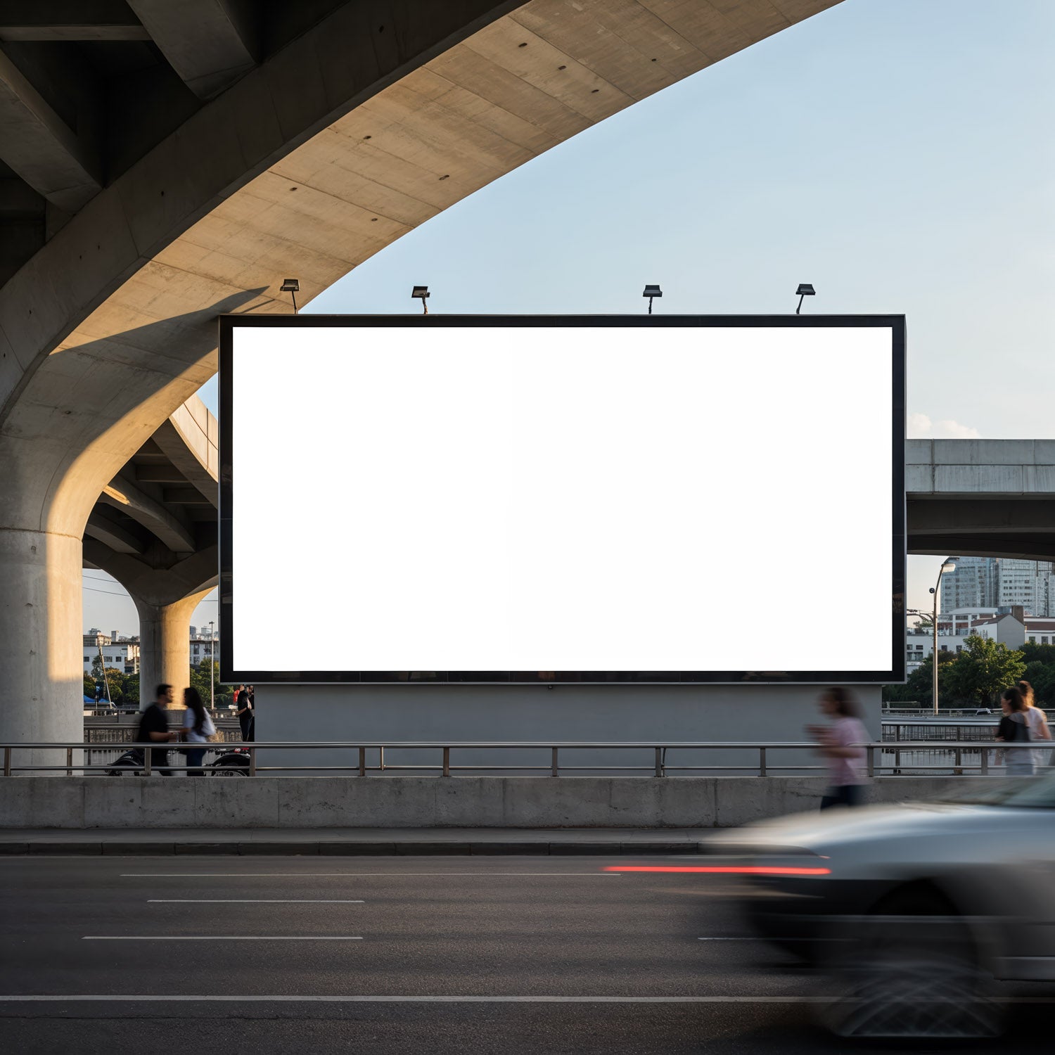 Duży, pusty billboard pod wiaduktem miejskim, przez który przejeżdżają samochody
