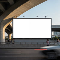Large blank billboard under urban overpass with passing traffic