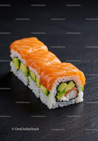 Fresh salmon avocado sushi rolls on dark surface