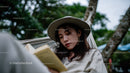 Relaxed Woman Reading a Book Amidst Green Foliage Outdoors