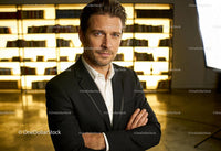 Confident man in suit posing against illuminated bookshelf