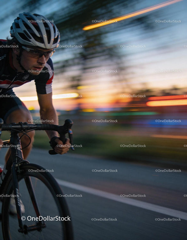 Focused cyclist racing at dusk on city road