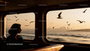 Woman gazing through ferry window at seagulls sunset