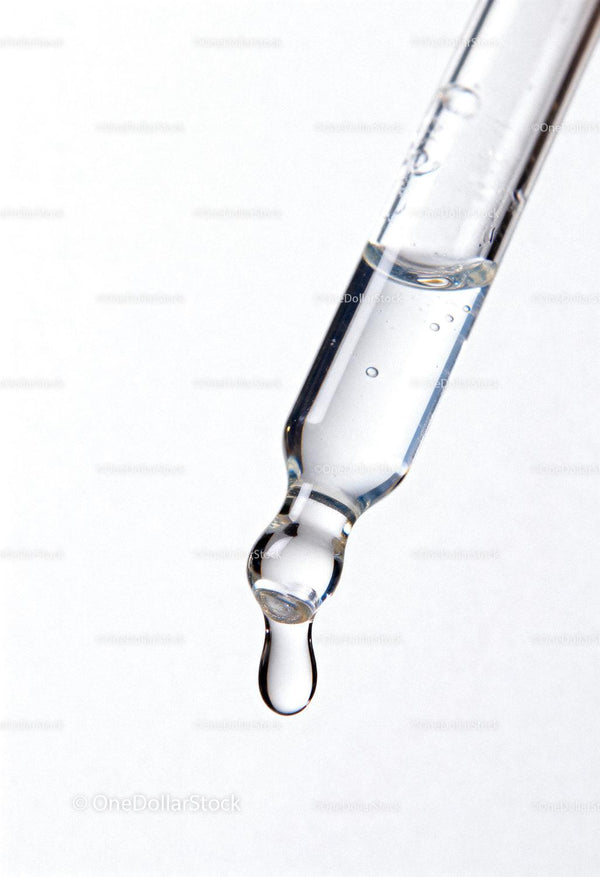 Zbliżenie kropli klarownego serum na szklanej pipetce