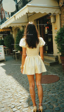 Fashionable Woman Walking in Cream Dress on Cobblestone Street