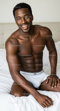 Smiling muscular man sitting on bed in white underwear