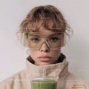 Young Woman with Curly Hair Wearing Goggles Drinking Green Smoothie