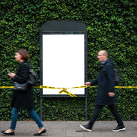 Blurred pedestrians pass blank billboard with caution tape