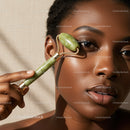 Elegant African Woman Using Jade Roller for Face Massage