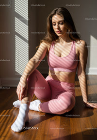 Young woman in pink activewear sitting on wooden floor