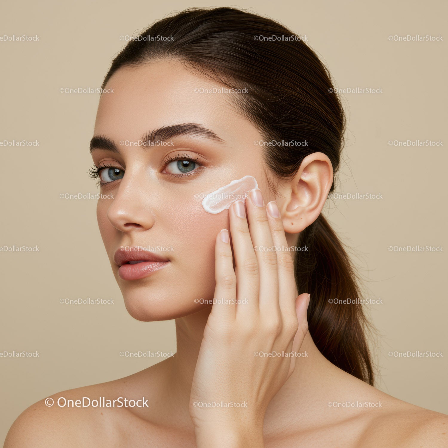 Young woman applying moisturizer on her face in skincare routine
