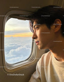 Young man gazing thoughtfully out airplane window