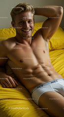 Smiling young man relaxing on yellow bed linen