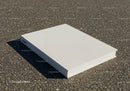 Closed white hardcover book lying on asphalt surface