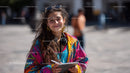 Smiling Young Woman with Colorful Jacket and Laptop in Outdoor City Scene