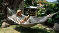 Woman Relaxing in Hammock in Lush Garden with Tropical Plants