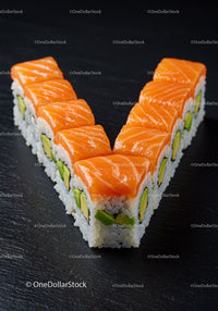 Fresh salmon avocado sushi rolls on black slate