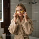 Young woman applying gold eye patches for skincare routine