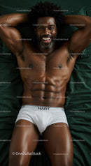 Smiling fit man relaxing on bed in white underwear