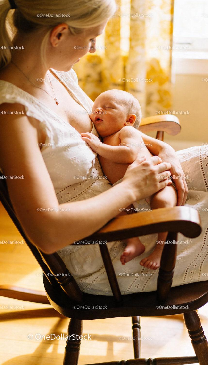 Mother gently breastfeeding her newborn baby in warm light