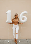 Teenage girl celebrating sixteenth birthday with balloons