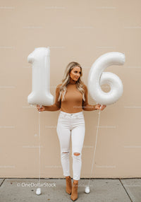 Teenage girl celebrating sixteenth birthday with balloons