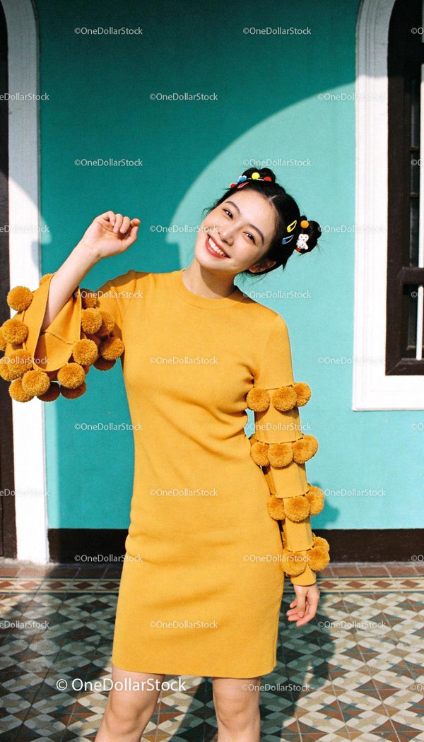 Smiling woman in mustard dress with pompom sleeves
