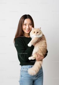 Smiling young woman holding fluffy cream cat