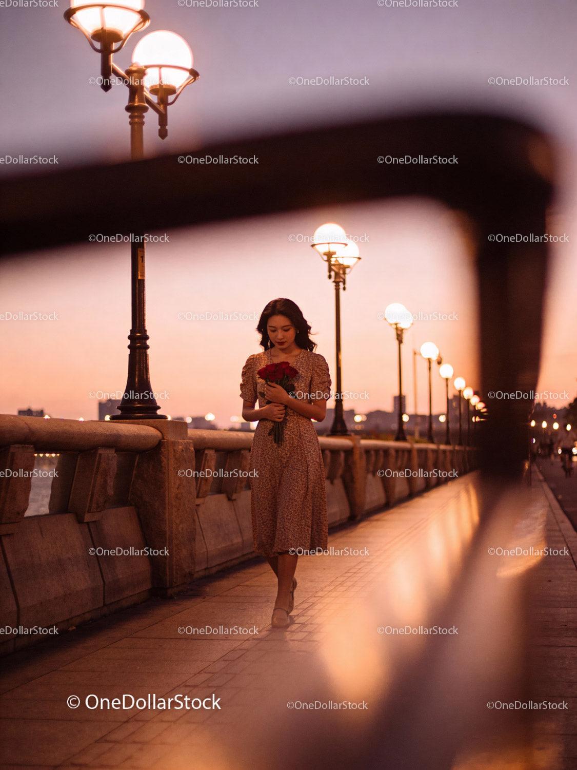 Woman holding red roses on illuminated city promenade