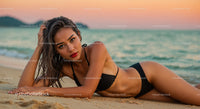 Elegant Woman in Black Bikini Lying on Beach at Sunset
