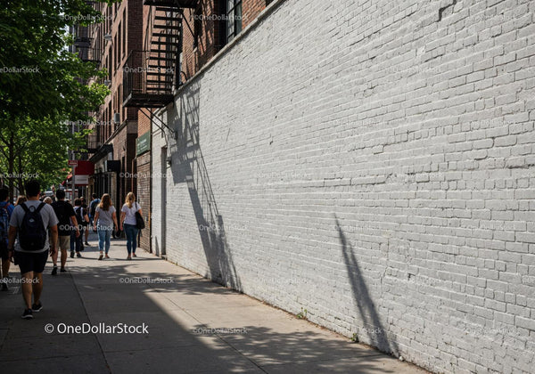 Urban Street Scene with Pedestrians and Brick Wall Shadows JPG Mockup Image