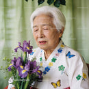 Elderly woman in traditional dress holding purple irises