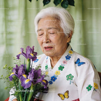 Elderly woman in traditional dress holding purple irises