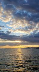 Scenic Sunset over Calm Ocean with Cloudy Sky and Reflection