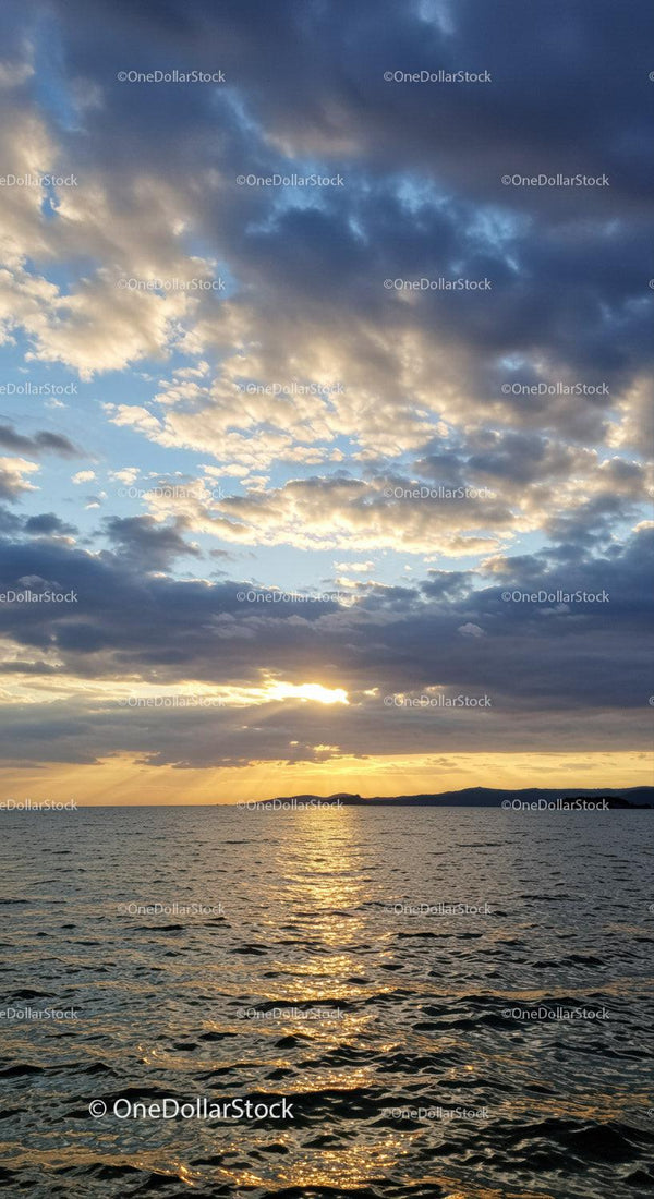Scenic Sunset over Calm Ocean with Cloudy Sky and Reflection