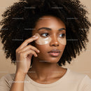 Close-up of a woman with curly hair applying under-eye patches for skincare