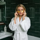 Young Woman Applying Gold Face Masks in Spa Bathroom