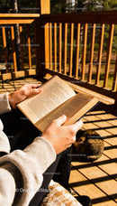 Person enjoying a book on a sunny wooden deck