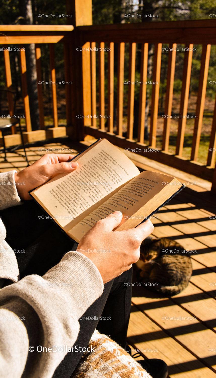Person enjoying a book on a sunny wooden deck