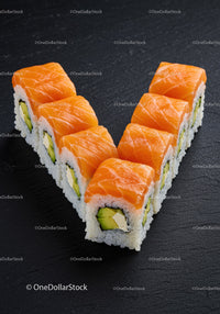 Fresh salmon sushi rolls arranged in V shape on black slate