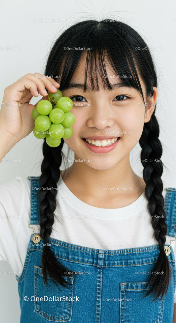 Joyful Young Girl with Braided Hair and Green Grapes in Hand