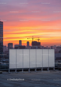 Colorful Sunset Over Modern City Skyline with Construction Cranes Rooftop View